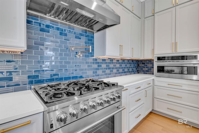 926 Inlet Cir, Gulf Shores, AL 36542 - kitchen featuring stainless steel appliances, wall chimney range hood, light countertops, and tasteful backsplash