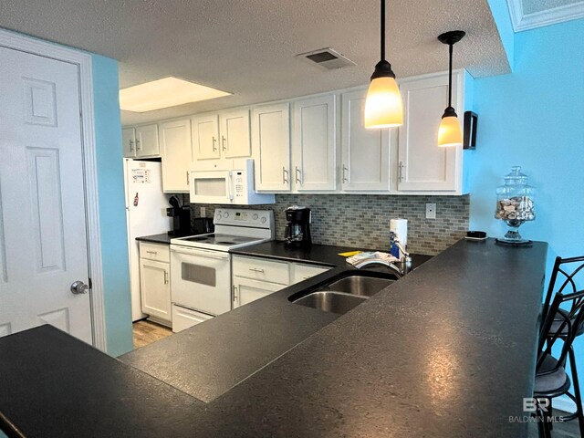 505 E Beach Blvd Unit 5-C, Gulf Shores, AL 36542 - kitchen with white appliances, decorative backsplash, white cabinets, dark countertops, and dark wood-style flooring