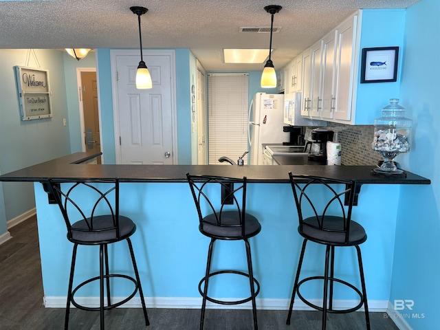 kitchen featuring tasteful backsplash, a textured ceiling, white appliances, and dark hardwood / wood-style floors