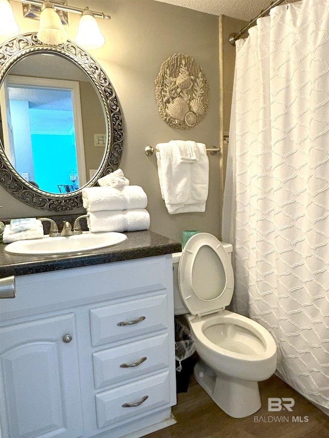 bathroom with a textured ceiling, toilet, vanity, and hardwood / wood-style floors