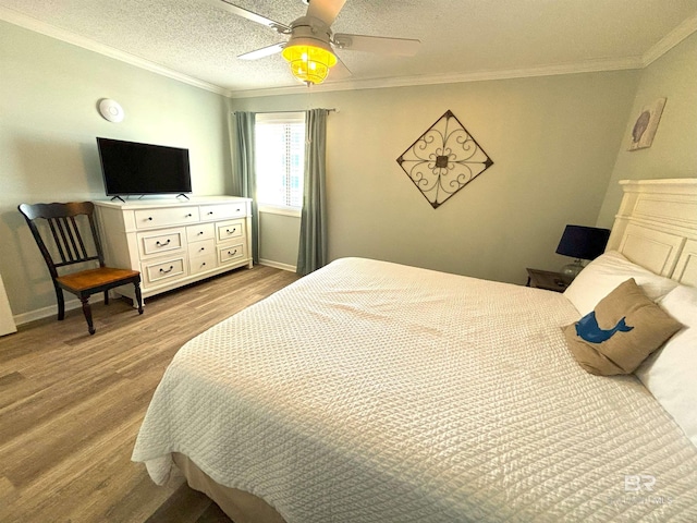 bedroom with ceiling fan, a textured ceiling, crown molding, and wood-type flooring