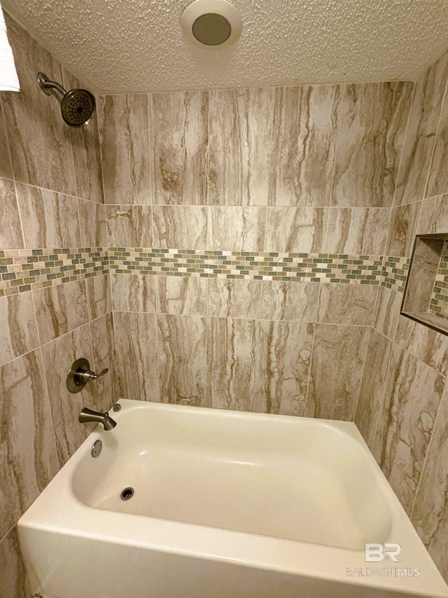 bathroom featuring tiled shower / bath and a textured ceiling