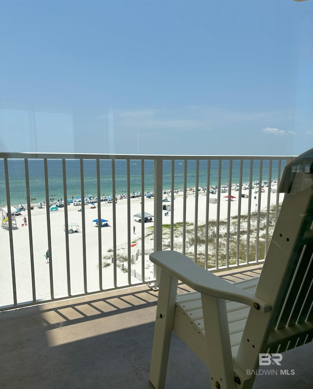 balcony with a water view and a view of the beach