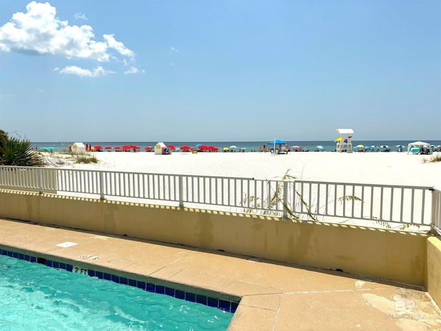 view of pool featuring a water view and a view of the beach