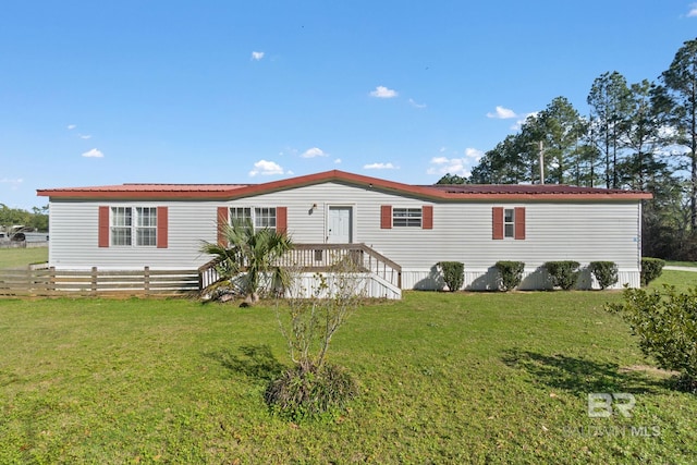 view of front facade with a front yard, metal roof, and fence