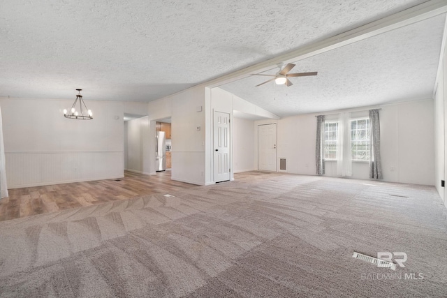 unfurnished living room featuring carpet, visible vents, vaulted ceiling, a textured ceiling, and ceiling fan with notable chandelier