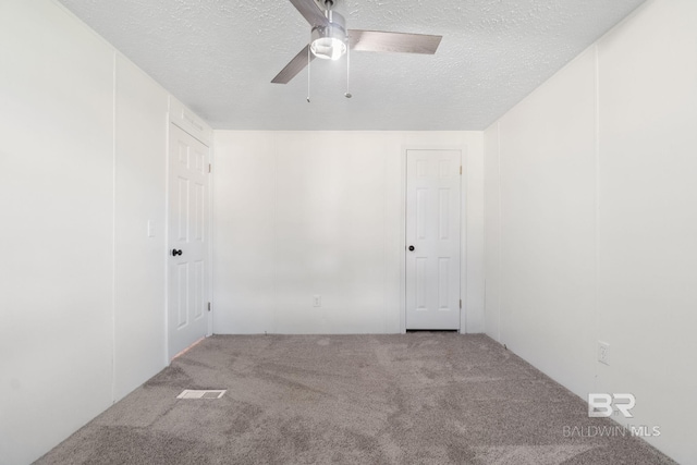 unfurnished room with a textured ceiling, carpet floors, and a ceiling fan