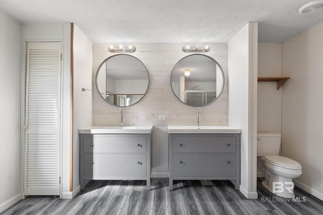 full bathroom featuring two vanities, visible vents, a sink, and wood finished floors