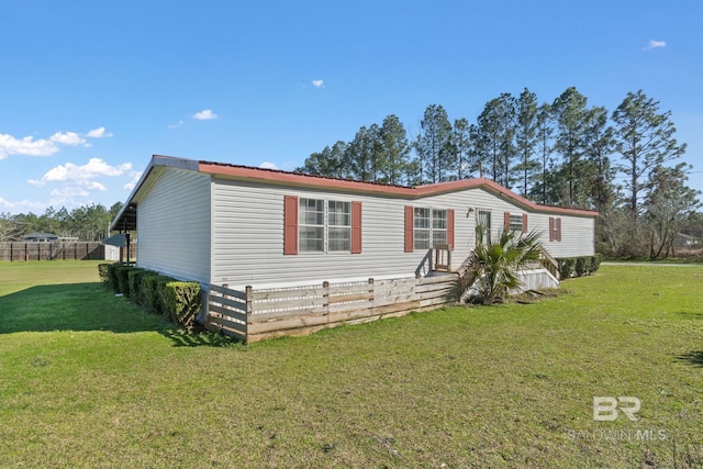 manufactured / mobile home featuring metal roof, a front lawn, and fence