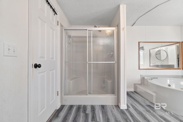 full bathroom featuring a textured ceiling, a stall shower, wood finished floors, and a bath