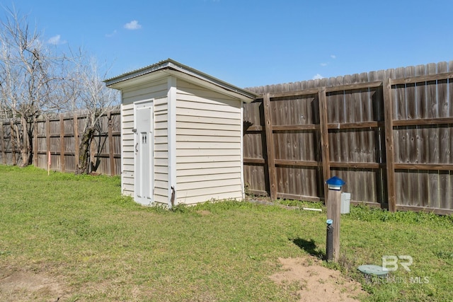 view of yard with a storage shed, a fenced backyard, and an outbuilding