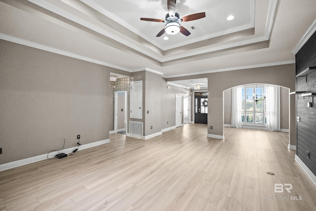 unfurnished living room with ceiling fan, ornamental molding, a raised ceiling, and light hardwood / wood-style floors