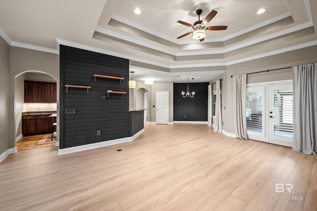 living room with ceiling fan with notable chandelier, light wood-type flooring, a tray ceiling, and crown molding