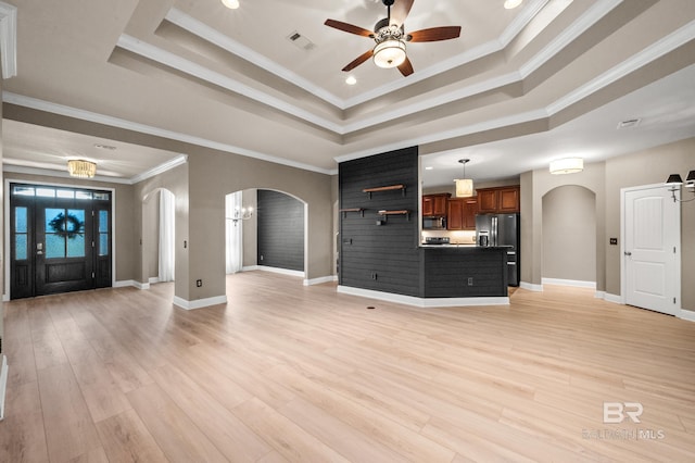 unfurnished living room featuring ceiling fan, light wood-type flooring, ornamental molding, and a tray ceiling