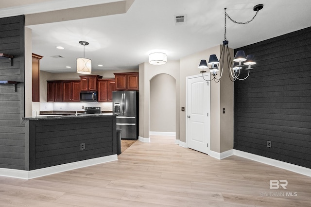 kitchen with hanging light fixtures, kitchen peninsula, black appliances, light hardwood / wood-style flooring, and a notable chandelier