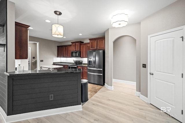 kitchen featuring light hardwood / wood-style flooring, stainless steel appliances, kitchen peninsula, and pendant lighting