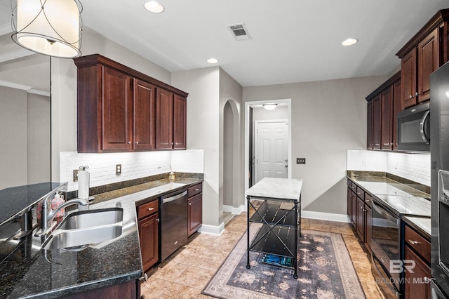 kitchen featuring dark stone counters, sink, hanging light fixtures, black appliances, and backsplash