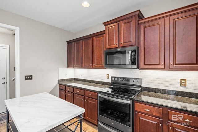 kitchen with appliances with stainless steel finishes, dark stone counters, a center island, and tasteful backsplash