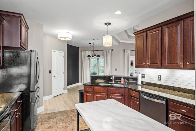 kitchen featuring appliances with stainless steel finishes, tasteful backsplash, light wood-type flooring, decorative light fixtures, and sink