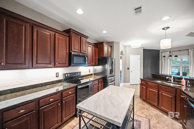 kitchen featuring pendant lighting, sink, stainless steel appliances, a center island, and dark stone countertops