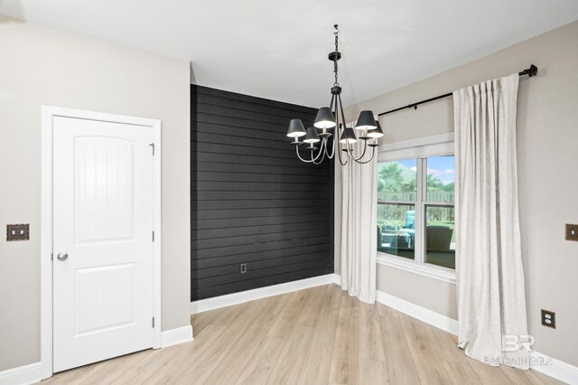 unfurnished dining area featuring an inviting chandelier and light hardwood / wood-style floors