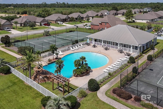 view of pool with a lawn and tennis court