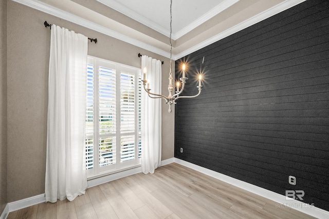 unfurnished dining area with a notable chandelier, light hardwood / wood-style floors, and crown molding