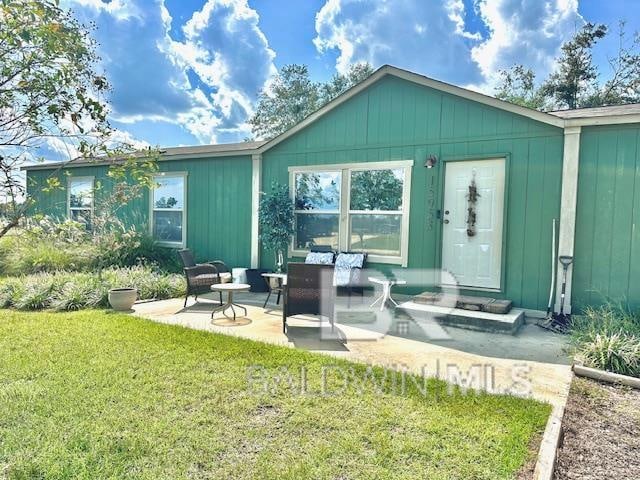 rear view of property featuring a yard and a patio area