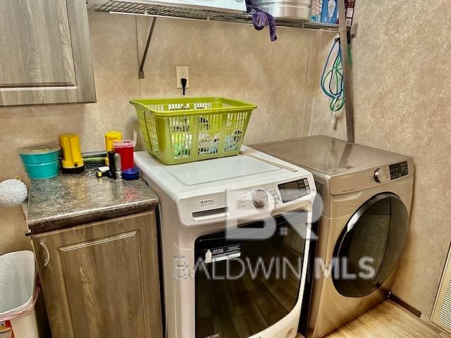 washroom with washing machine and clothes dryer and cabinets