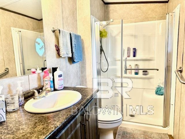 bathroom featuring vanity, ornamental molding, toilet, and a shower with door