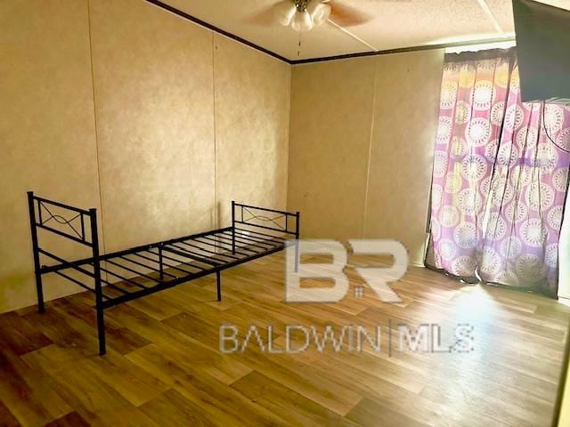 unfurnished bedroom with ornamental molding, hardwood / wood-style floors, and ceiling fan