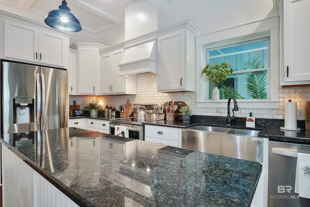 kitchen featuring sink, white cabinetry, hanging light fixtures, dark stone countertops, and stainless steel appliances