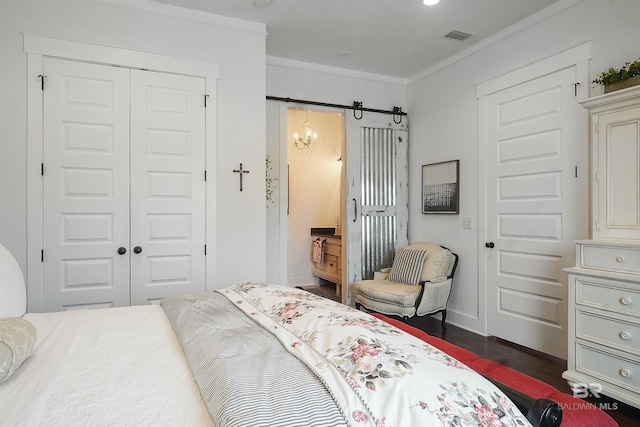 bedroom featuring ornamental molding, a barn door, dark hardwood / wood-style flooring, and a closet