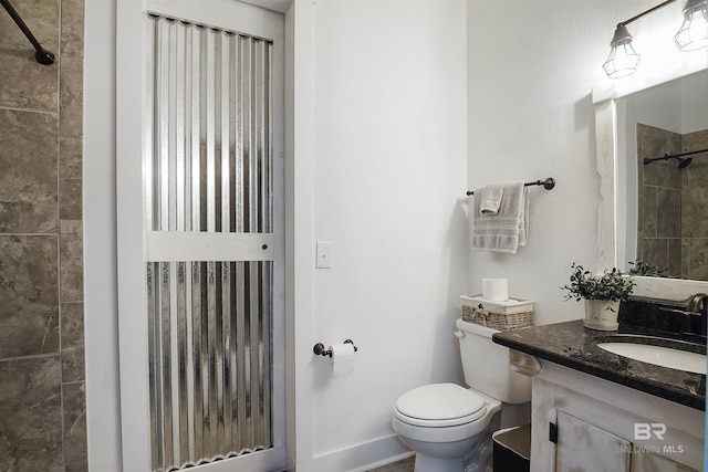 bathroom featuring tiled shower, vanity, and toilet