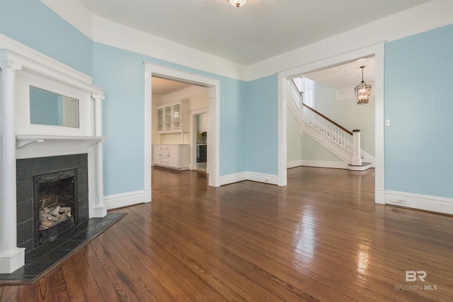 1206 Palmetto St, Mobile, AL 36604 - unfurnished living room featuring a tiled fireplace, stairs, hardwood / wood-style flooring, and baseboards