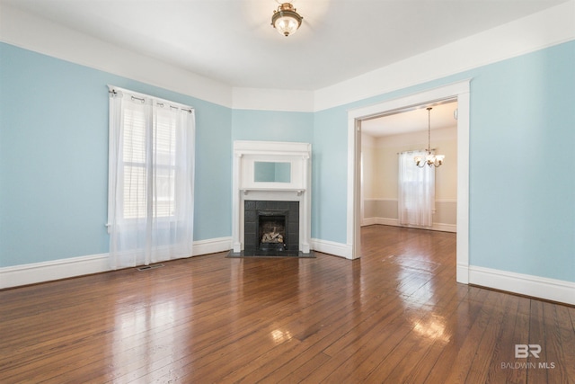 1206 Palmetto St, Mobile, AL 36604 - unfurnished living room with a tiled fireplace, a chandelier, wood-type flooring, and baseboards