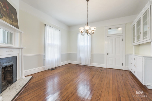 1206 Palmetto St, Mobile, AL 36604 - unfurnished dining area with a chandelier, a fireplace with raised hearth, dark wood-style floors, and baseboards