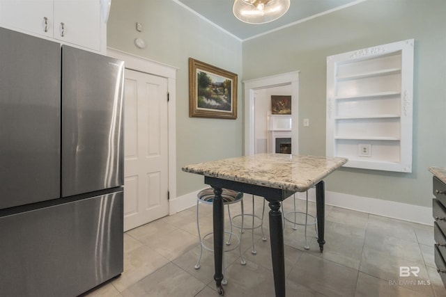 1206 Palmetto St, Mobile, AL 36604 - kitchen featuring freestanding refrigerator, light tile patterned flooring, a fireplace, baseboards, and white cabinets