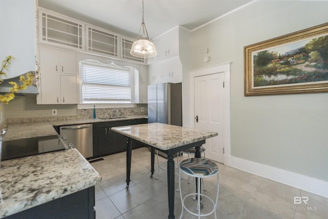 1206 Palmetto St, Mobile, AL 36604 - kitchen featuring appliances with stainless steel finishes, white cabinets, decorative light fixtures, tasteful backsplash, and a kitchen bar