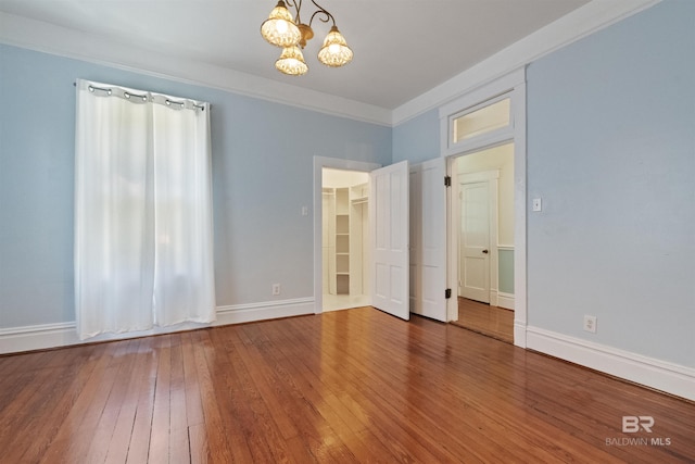 1206 Palmetto St, Mobile, AL 36604 - unfurnished bedroom with a chandelier, hardwood / wood-style floors, baseboards, and a walk in closet