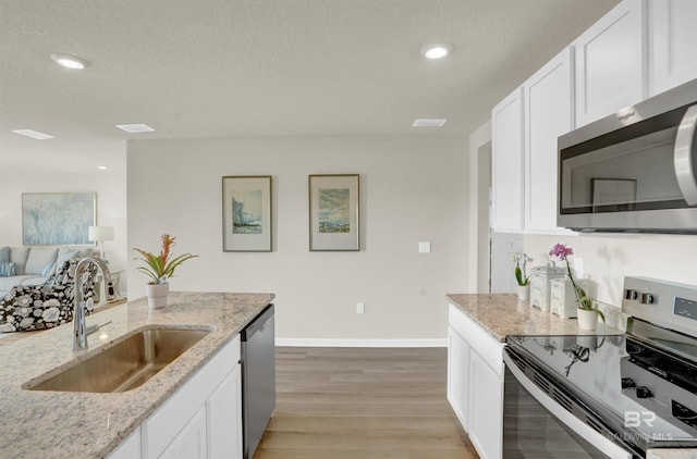 1044 Hayward Loop, Foley, AL 36535 - kitchen featuring stainless steel appliances, white cabinetry, light wood-style flooring, recessed lighting, and a textured ceiling