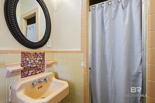 bathroom with walk in shower, sink, and tile walls