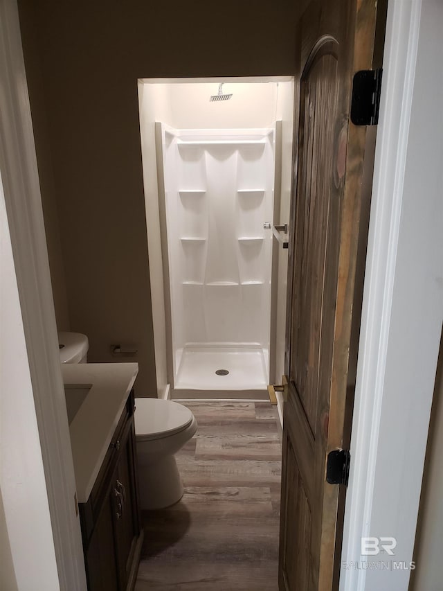 bathroom with toilet, hardwood / wood-style floors, vanity, and a shower