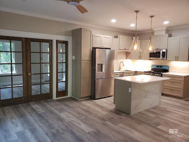 kitchen with appliances with stainless steel finishes, hanging light fixtures, light wood-type flooring, and a kitchen island