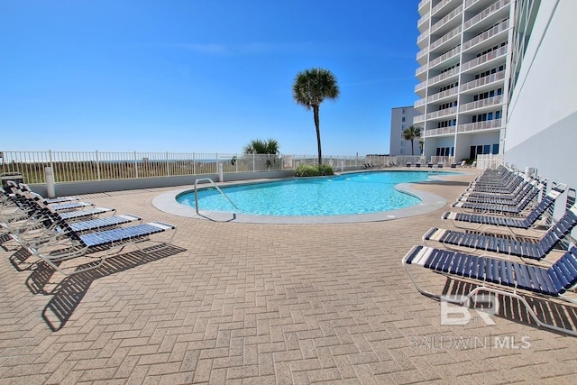 pool with a patio area and fence