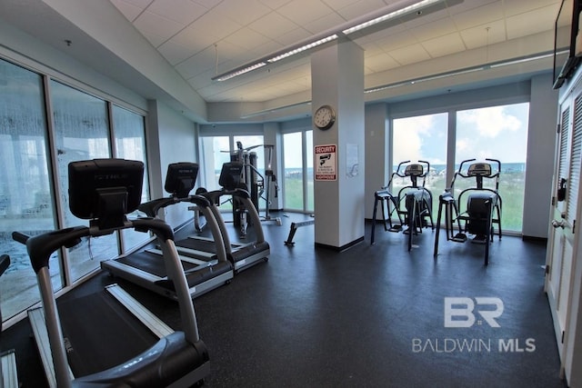 workout area featuring a paneled ceiling and baseboards