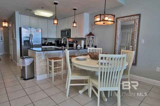 kitchen featuring light tile patterned floors, appliances with stainless steel finishes, dark countertops, and backsplash