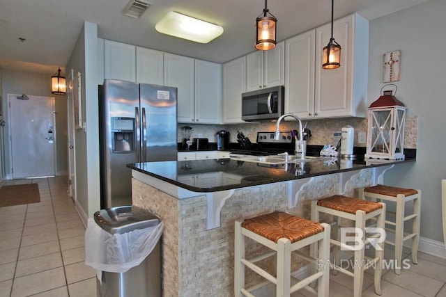 kitchen with light tile patterned floors, tasteful backsplash, visible vents, a peninsula, and stainless steel appliances