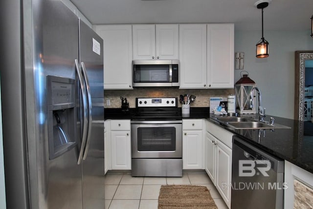 kitchen with light tile patterned floors, backsplash, appliances with stainless steel finishes, white cabinets, and a sink