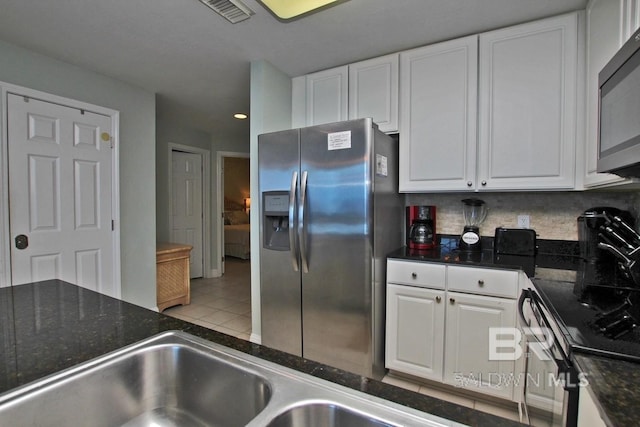 kitchen featuring tile patterned flooring, stainless steel appliances, visible vents, white cabinetry, and backsplash